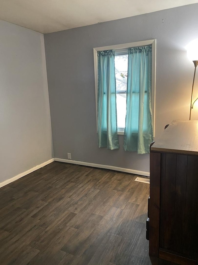 unfurnished room featuring dark wood finished floors, baseboards, and visible vents