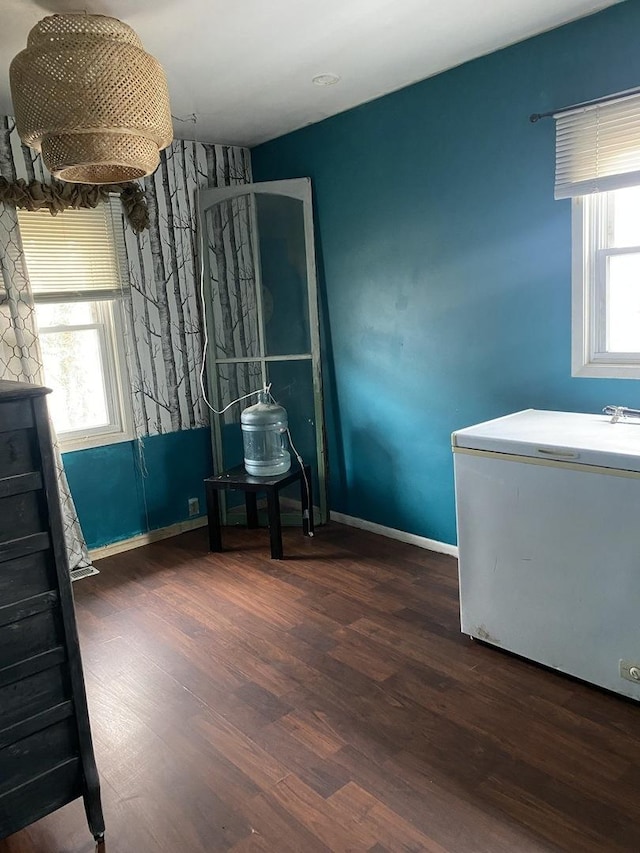 bedroom with multiple windows, wood finished floors, and baseboards