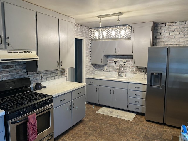 kitchen with tasteful backsplash, exhaust hood, appliances with stainless steel finishes, a sink, and gray cabinetry