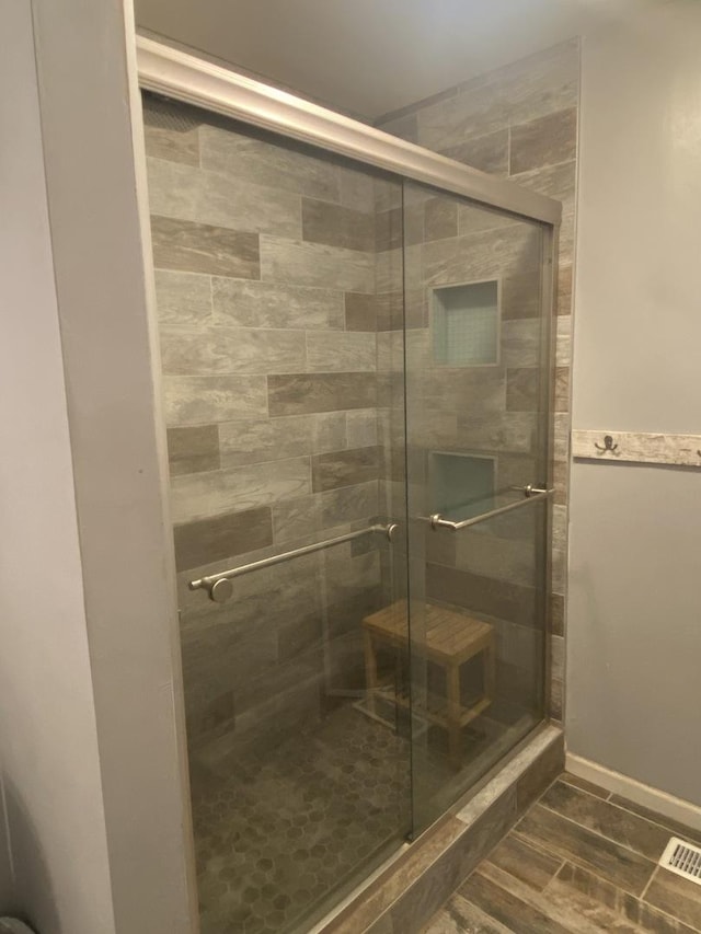full bath with wood finished floors, visible vents, and a stall shower