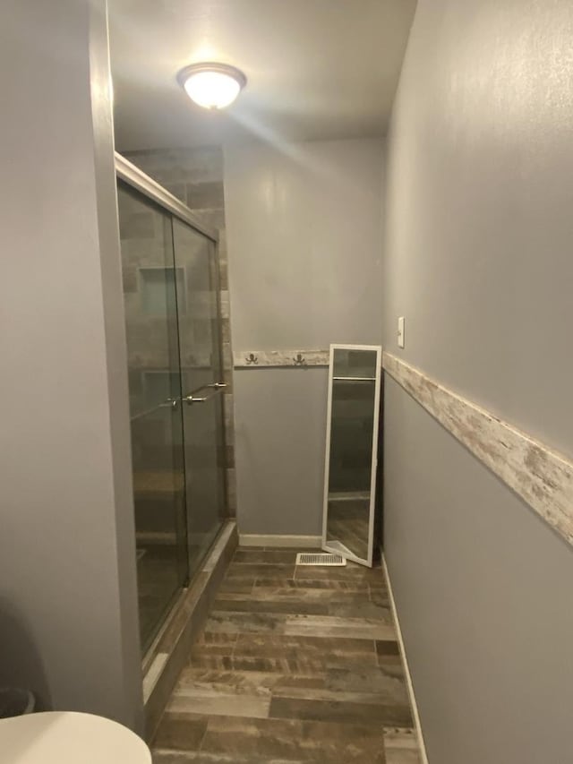 full bathroom with wood finished floors, toilet, and a stall shower
