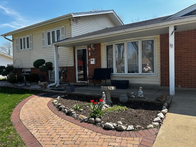 split level home featuring a porch and brick siding