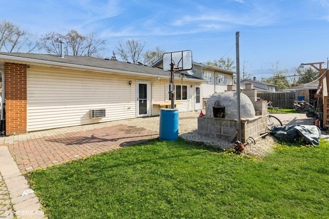 rear view of house with a lawn, brick siding, fence, and a patio area