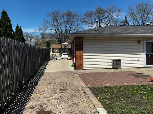 view of property exterior with fence, a shingled roof, and brick siding