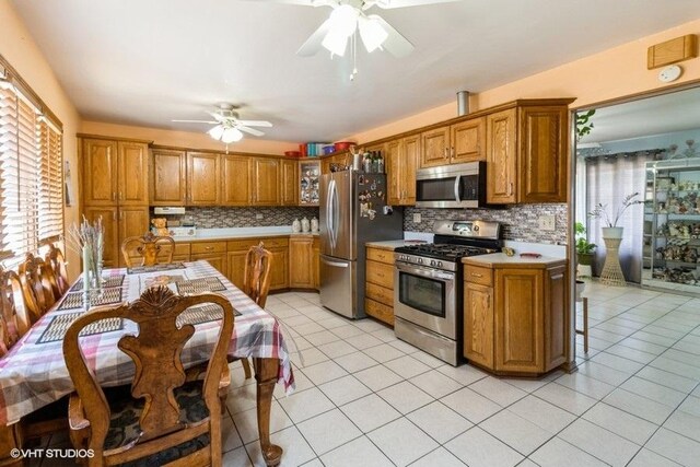 kitchen featuring ceiling fan, brown cabinets, stainless steel appliances, and light countertops
