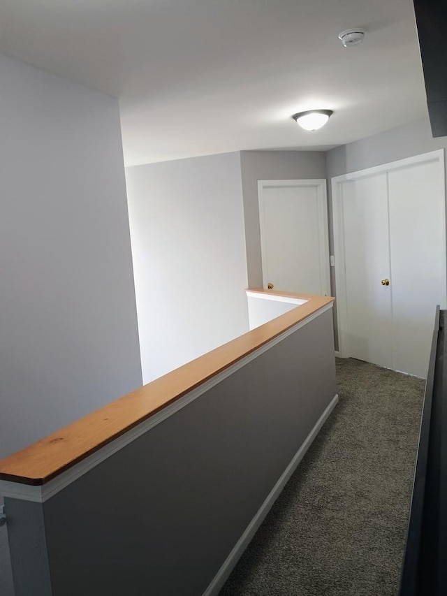 hallway with an upstairs landing and dark colored carpet