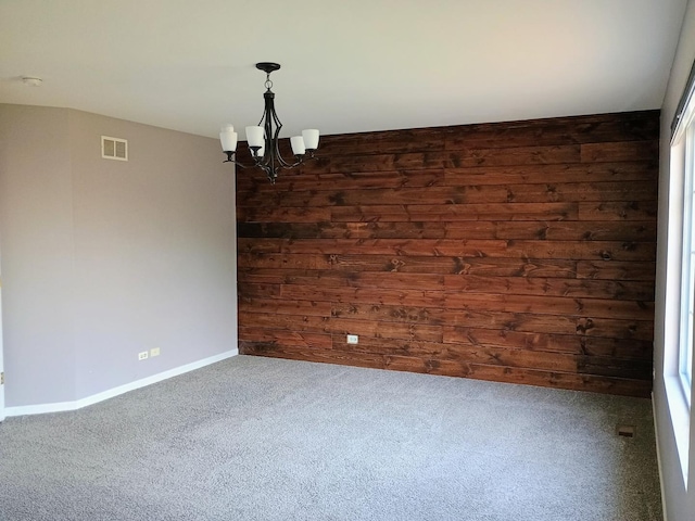 carpeted spare room with an inviting chandelier, visible vents, and baseboards
