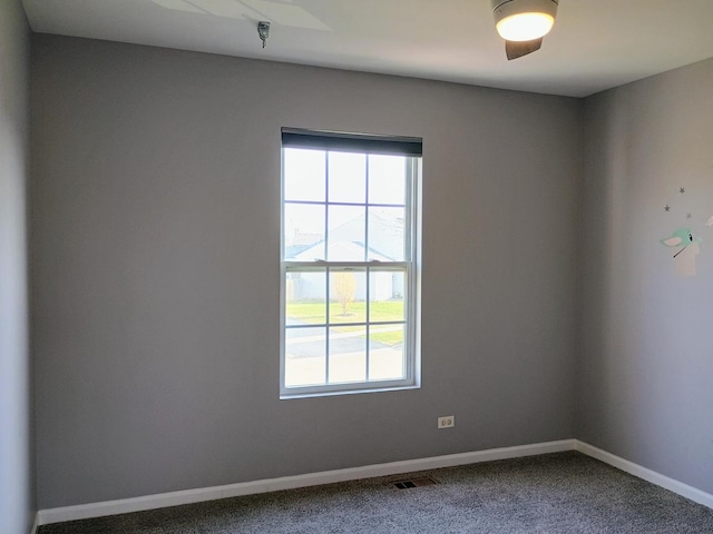 spare room featuring baseboards, dark colored carpet, and visible vents