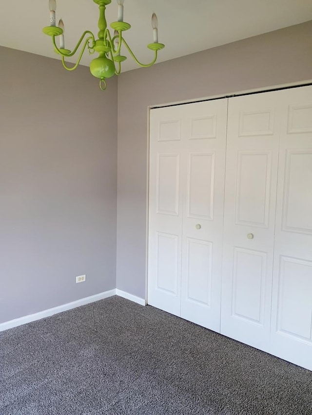 unfurnished bedroom featuring a closet, dark carpet, and baseboards