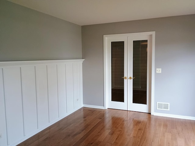 spare room with wood finished floors, visible vents, french doors, and baseboards