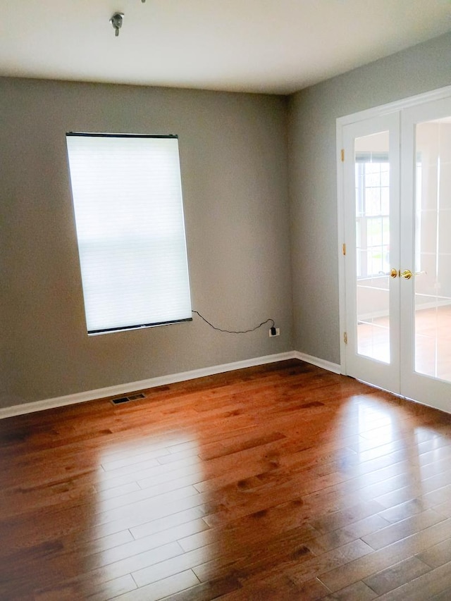 spare room with baseboards, visible vents, wood finished floors, and french doors