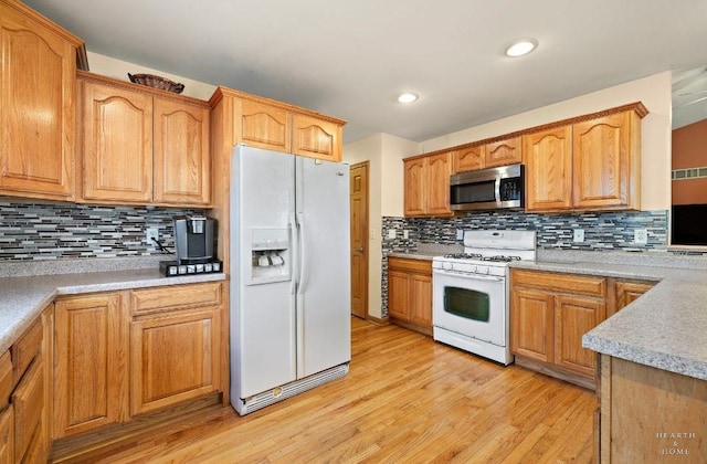 kitchen with light wood-style floors, decorative backsplash, white appliances, and light countertops