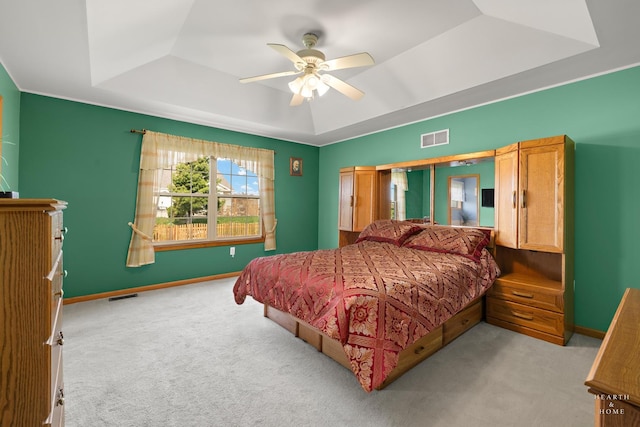 bedroom with visible vents, carpet floors, and a tray ceiling
