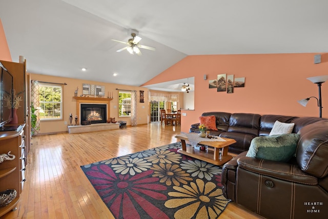living room featuring a glass covered fireplace, ceiling fan, lofted ceiling, and a wealth of natural light