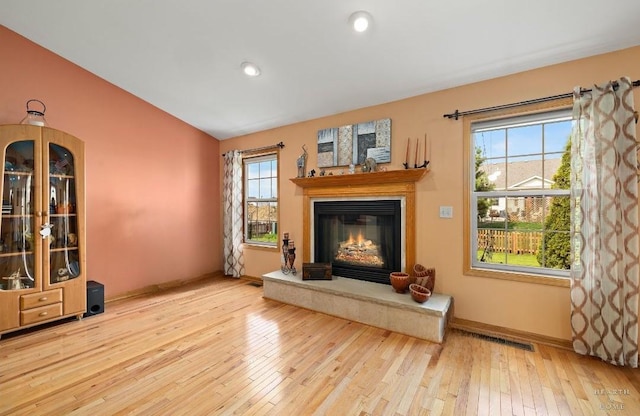 unfurnished living room with a glass covered fireplace, lofted ceiling, baseboards, recessed lighting, and hardwood / wood-style flooring