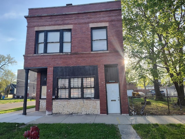 view of front of home with brick siding, fence, and stone siding