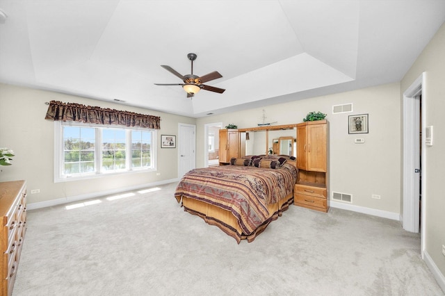 bedroom featuring visible vents, a tray ceiling, and light carpet