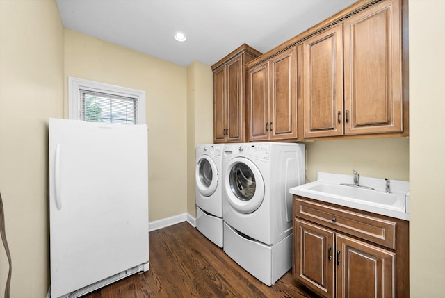 washroom featuring a sink, washing machine and dryer, baseboards, cabinet space, and dark wood-type flooring