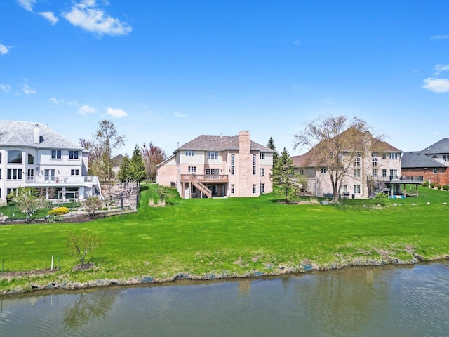 rear view of house with a lawn, a water view, and a chimney