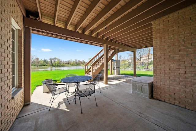 view of patio / terrace with outdoor dining space, stairs, and a water view