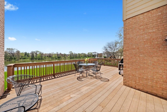 deck with a yard, a water view, and outdoor dining area