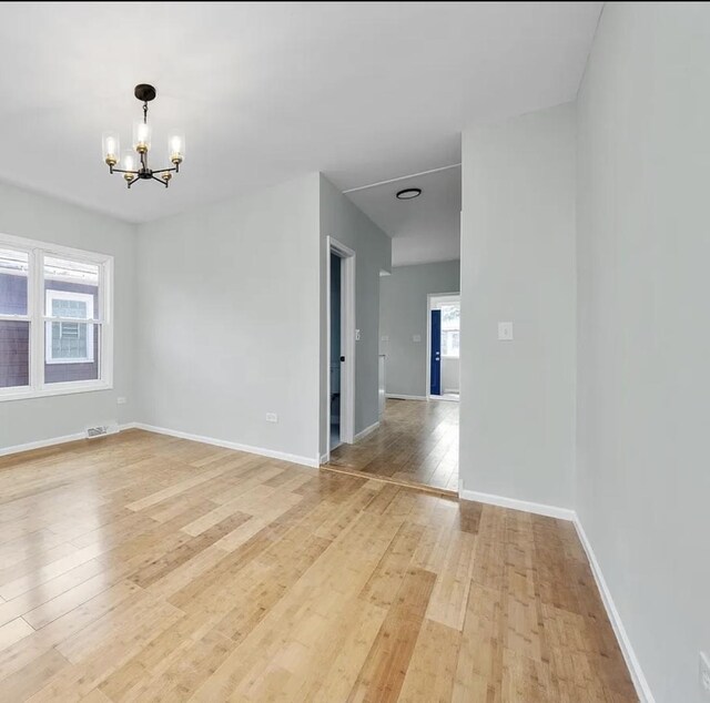 11414 S Wallace St, Chicago, IL 60628 - unfurnished room with a chandelier, light wood finished floors, and baseboards
