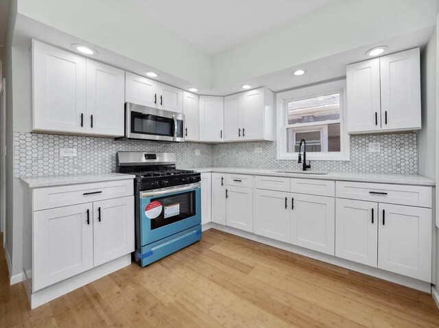 11414 S Wallace St, Chicago, IL 60628 - kitchen with appliances with stainless steel finishes, a sink, light wood finished floors, white cabinets, and recessed lighting