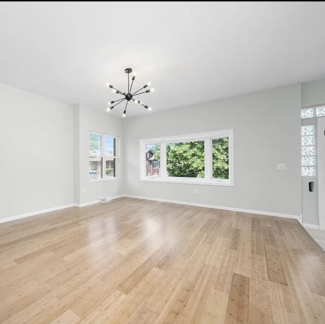 11414 S Wallace St, Chicago, IL 60628 - unfurnished living room with a chandelier, light wood-style flooring, and baseboards