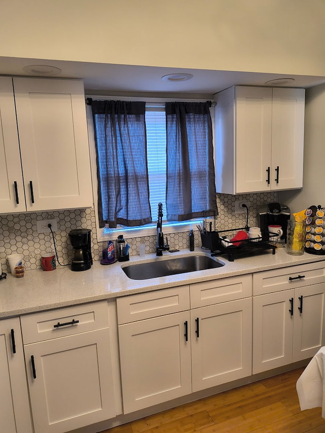 11414 S Wallace St, Chicago, IL 60628 - kitchen featuring a sink, white cabinets, decorative backsplash, light wood finished floors, and light stone counters