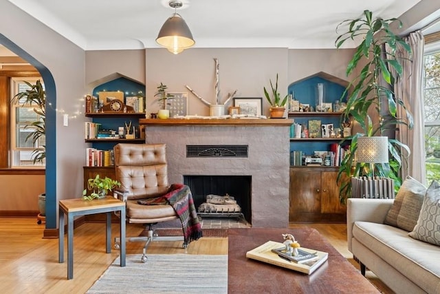 living area with arched walkways, wood finished floors, and a fireplace