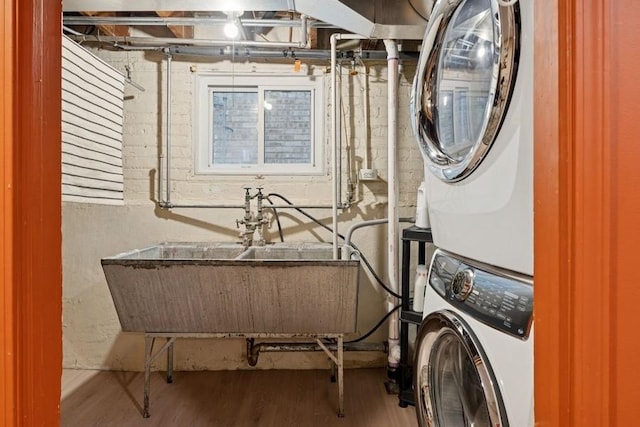 laundry room with laundry area, stacked washer and dryer, and wood finished floors