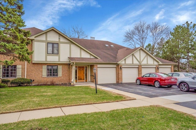 tudor home with stucco siding, brick siding, a garage, driveway, and a front yard