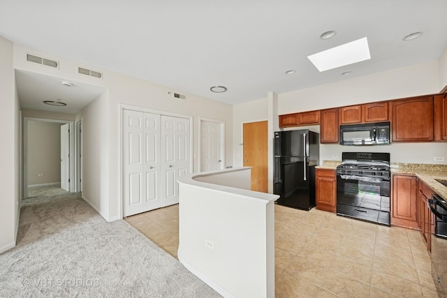 3501 Wellington Ct Unit 410, Rolling Meadows, IL 60008 - kitchen featuring black appliances, a skylight, brown cabinets, light tile patterned floors, and light carpet