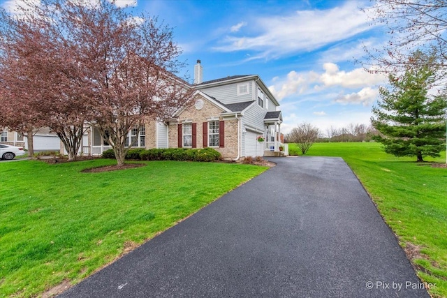 obstructed view of property featuring driveway, a chimney, a front yard, brick siding, and an attached garage