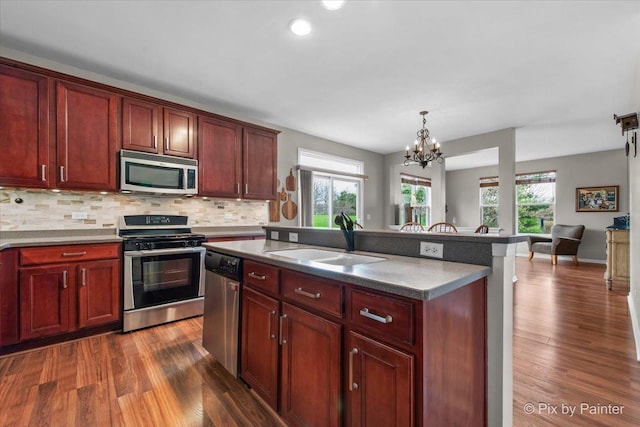 kitchen with a sink, tasteful backsplash, stainless steel appliances, and dark wood-type flooring
