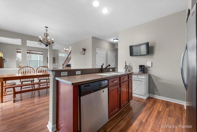 kitchen featuring dark wood-style flooring, a notable chandelier, a sink, stainless steel appliances, and baseboards