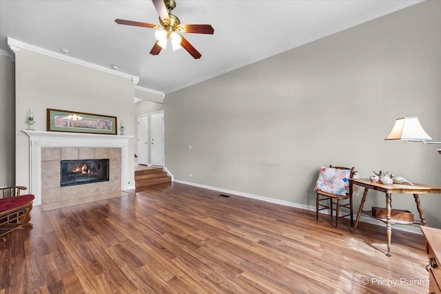 interior space featuring crown molding, a ceiling fan, wood finished floors, and a fireplace