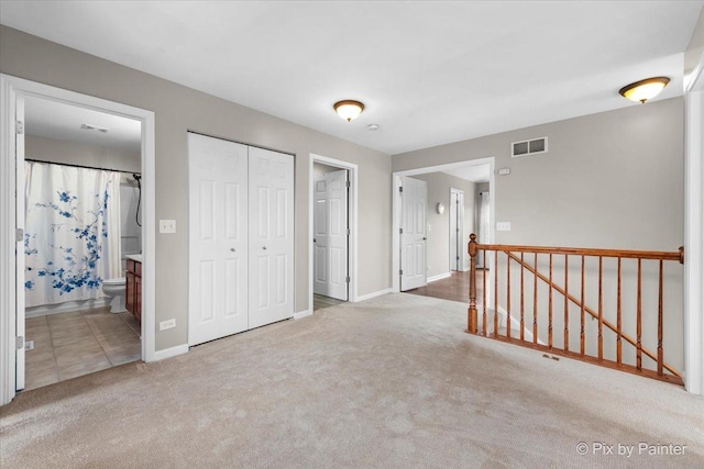 interior space with visible vents, carpet floors, baseboards, a closet, and connected bathroom