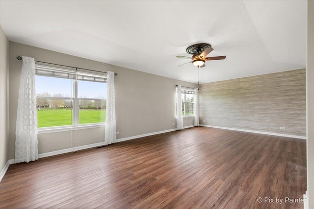 spare room featuring baseboards, a ceiling fan, wood finished floors, and visible vents
