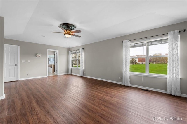 interior space with baseboards, a ceiling fan, wood finished floors, and visible vents