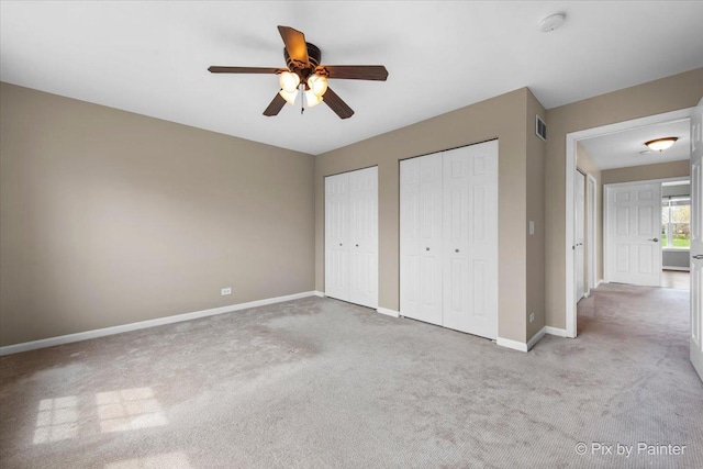 unfurnished bedroom with visible vents, multiple closets, baseboards, ceiling fan, and carpet flooring