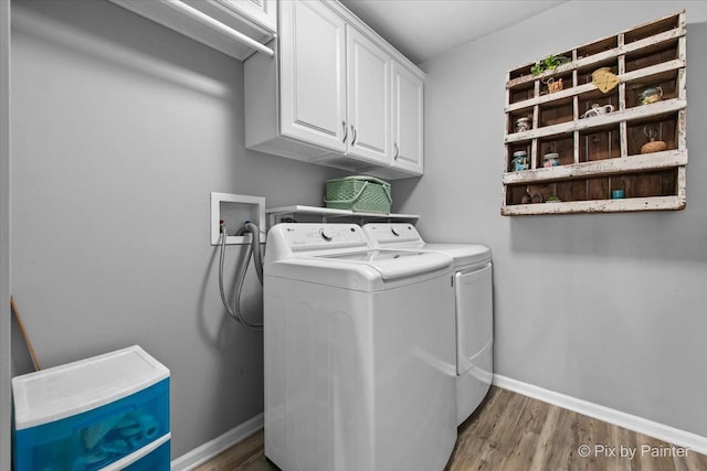 laundry room with washing machine and clothes dryer, baseboards, wood finished floors, and cabinet space