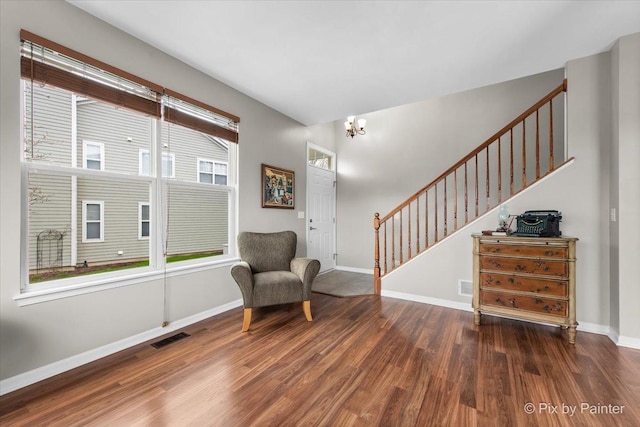 sitting room with visible vents, wood finished floors, stairway, baseboards, and a notable chandelier