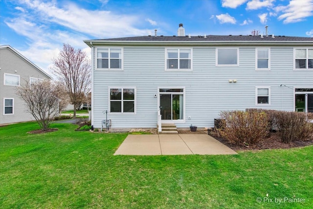 rear view of house featuring a patio, a yard, a chimney, and entry steps
