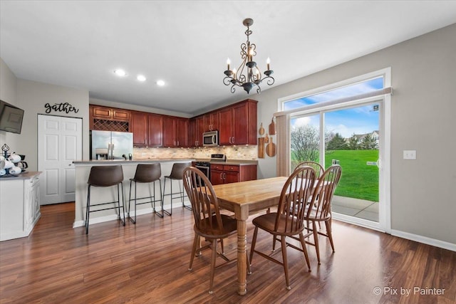 dining room with recessed lighting, baseboards, a notable chandelier, and dark wood-type flooring