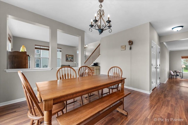 dining space featuring baseboards, wood finished floors, a chandelier, and stairway