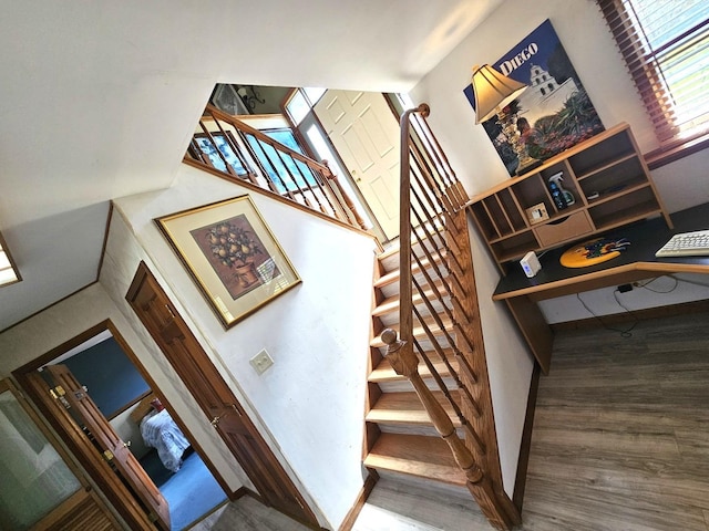 stairs with a towering ceiling, wood finished floors, and baseboards