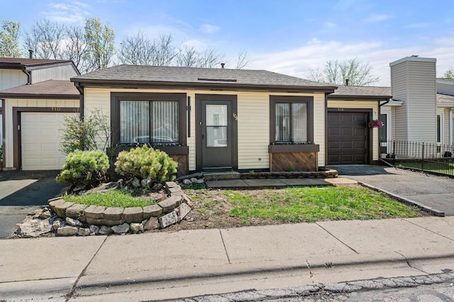 view of front of property featuring fence, aphalt driveway, a shingled roof, and an attached garage