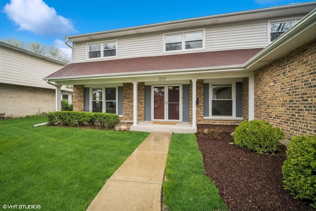 traditional-style home with brick siding, a front yard, and a porch