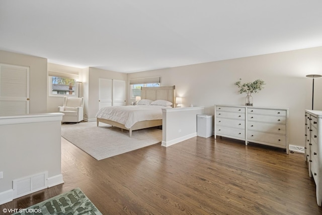 bedroom featuring baseboards, multiple windows, wood finished floors, and visible vents